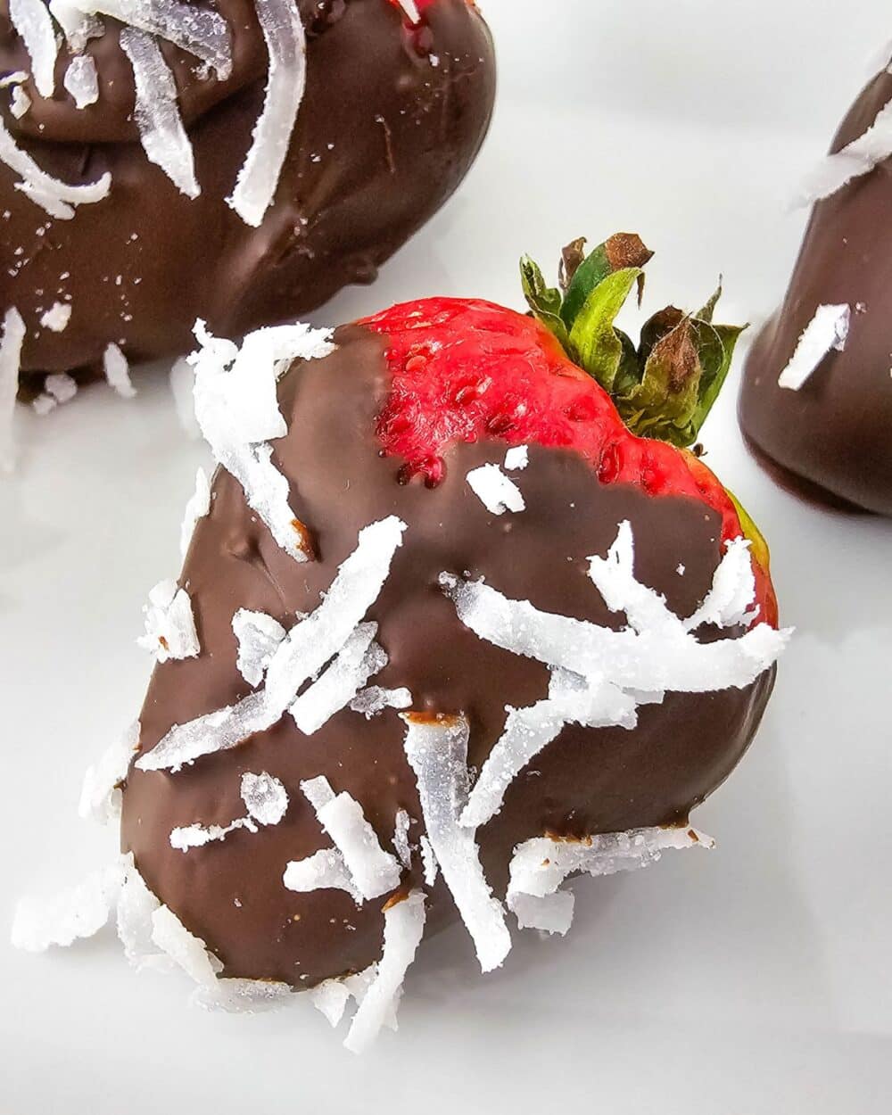 strawberries covered in sugar free melted chocolate and unsweetened coconut on plate