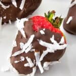 strawberries covered in sugar free melted chocolate and unsweetened coconut on plate