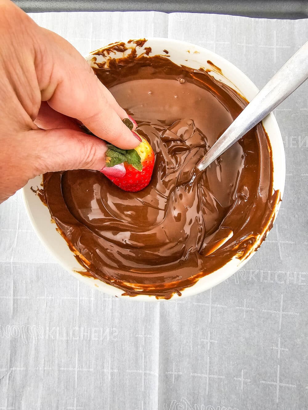 dipping a strawberry in melted sugar free chocolate