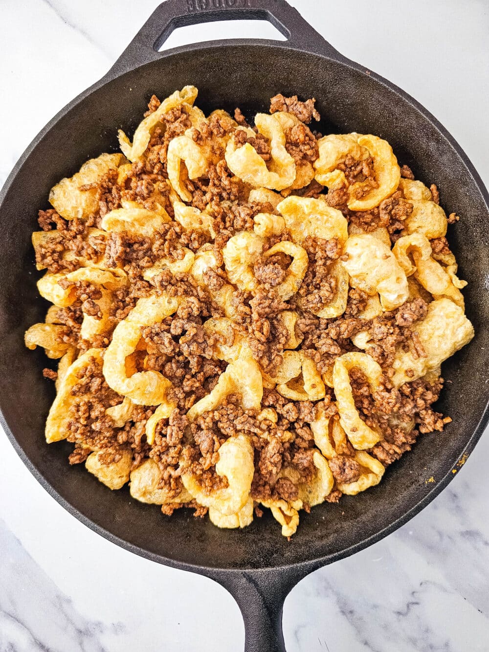 pork rinds and ground beef in iron skillet