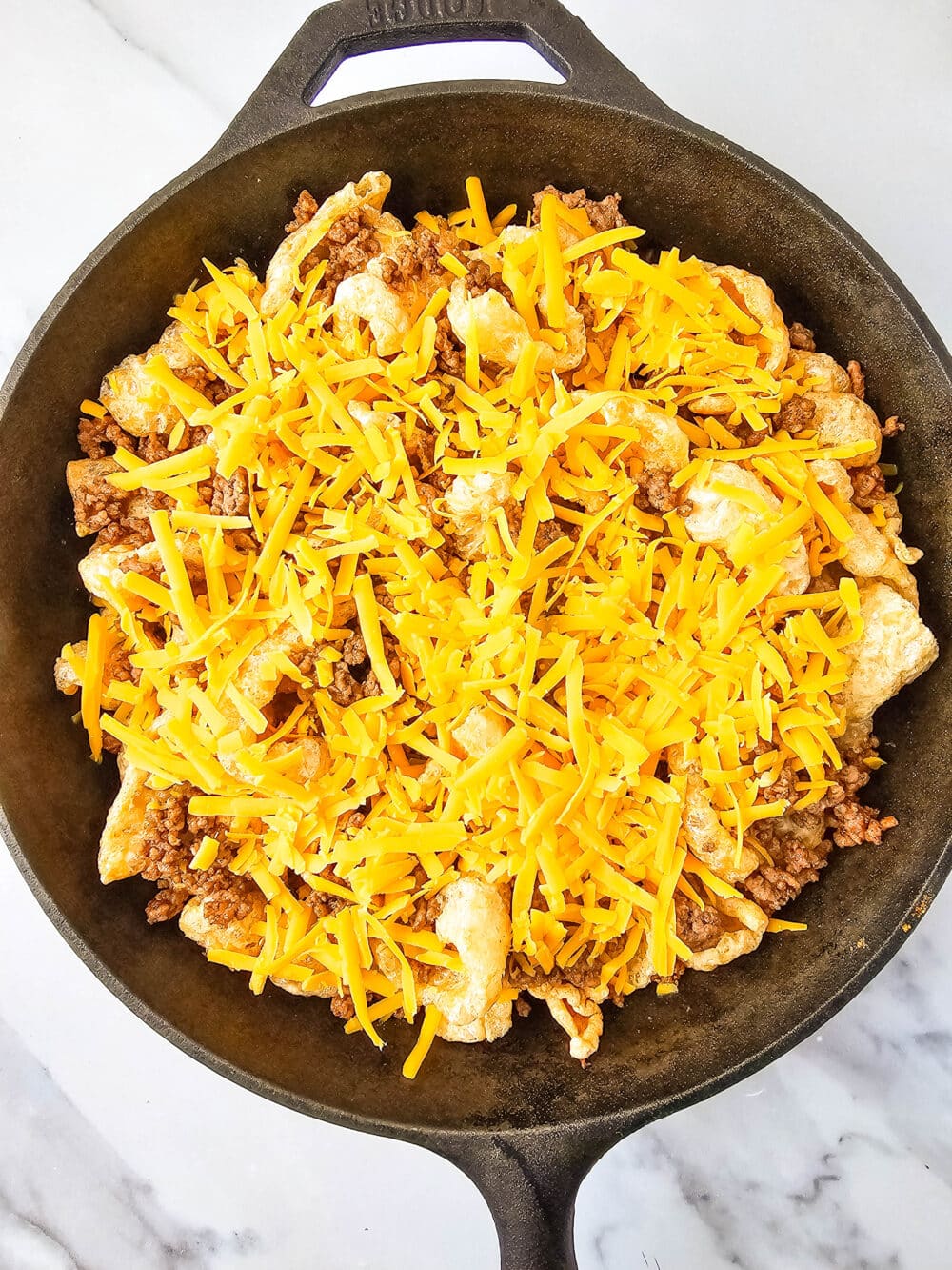 pork rinds and ground beef and cheese in iron skillet