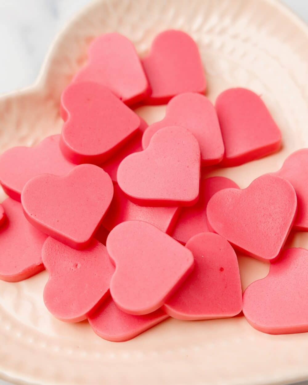 close up of keto strawberry heart-shaped gummies on a plate