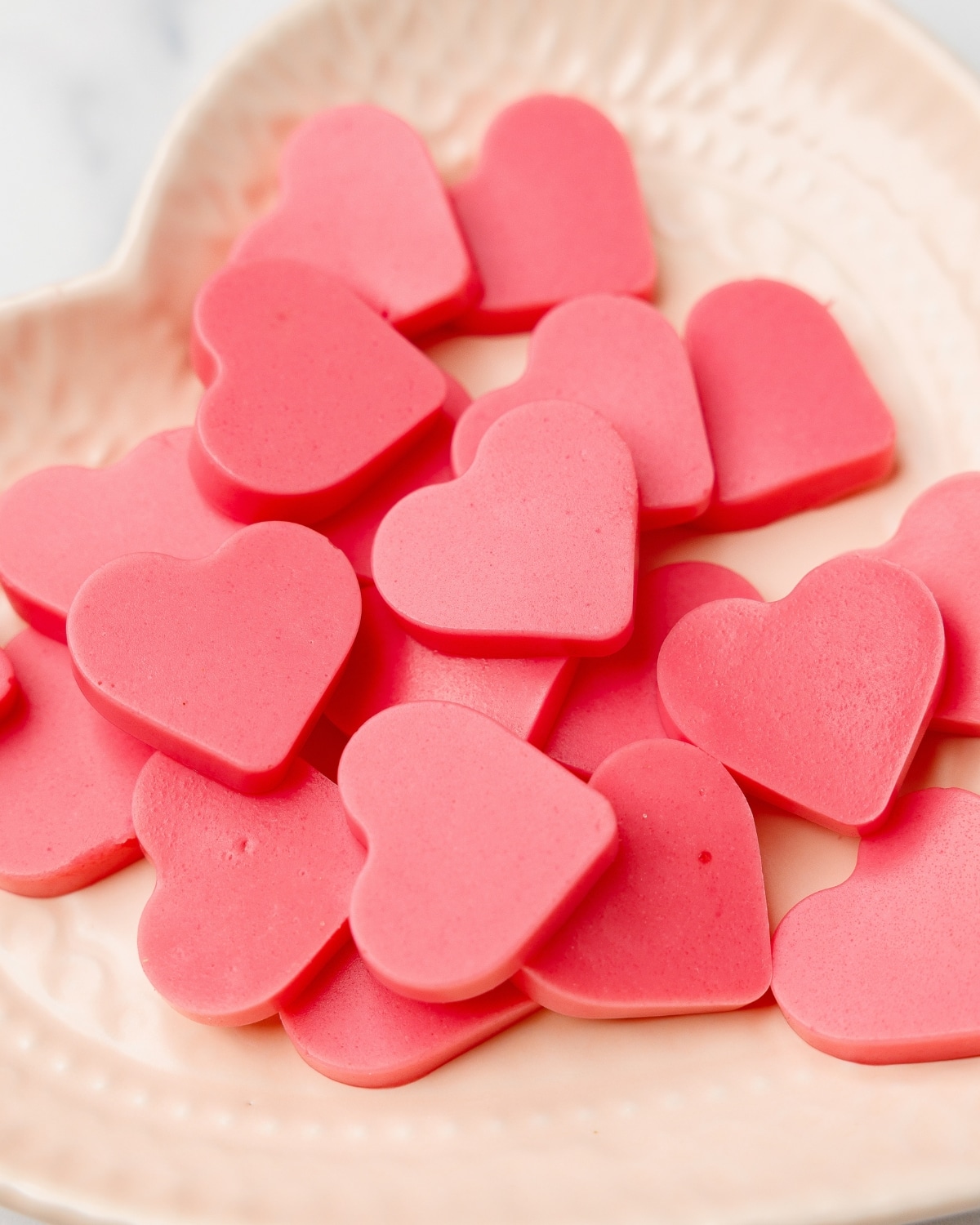 close up of keto strawberry heart-shaped gummies on a plate