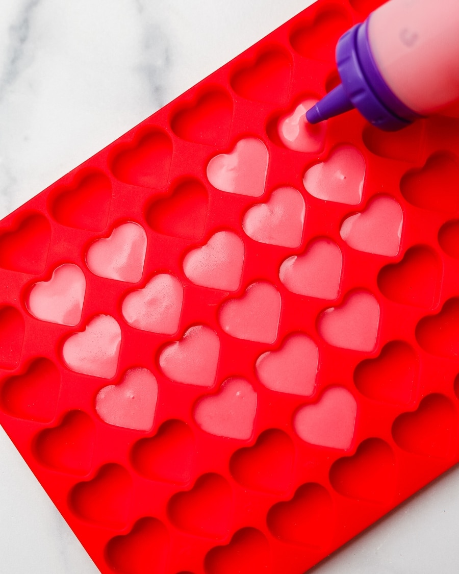 putting Keto Strawberry Gummies into mini heart-shaped red silicone mold