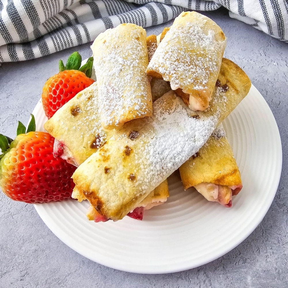 Keto Air Fryer Strawberry Cheesecake Roll Ups on a plate with strawberries