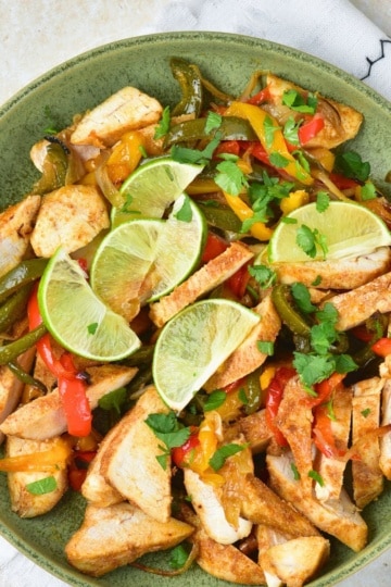Easy Chicken Fajitas with lime and pepper slices in a green bowl overhead view