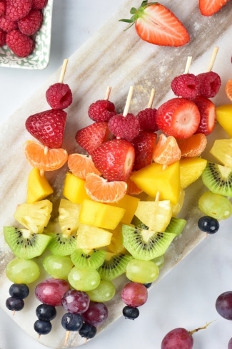 Rainbow Fruit Skewers on a gray cutting board overhead shot