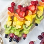 Rainbow Fruit Skewers on a marble cutting board overhead view with grapes nearby