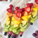 Rainbow Fruit Skewers on a gray cutting board overhead shot