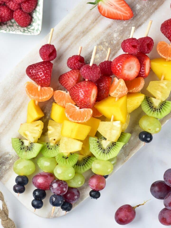 Rainbow Fruit Skewers on a gray cutting board overhead shot