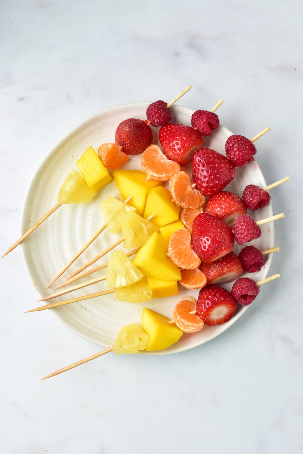 raspberries and strawberries and oranges and pineapple on skewer
