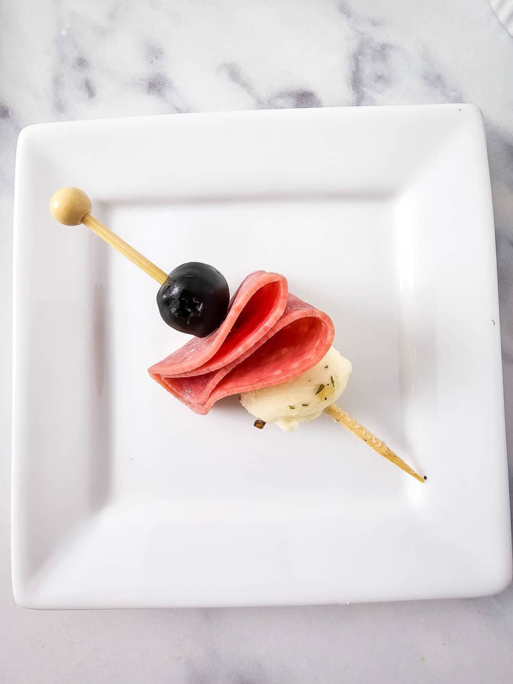 olive, salami, and mozzarella ball on a skewer