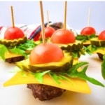 side view of Keto Mini Cheeseburger Bites stacked with tomato, pickle, cheese, lettuce, and a mini burger