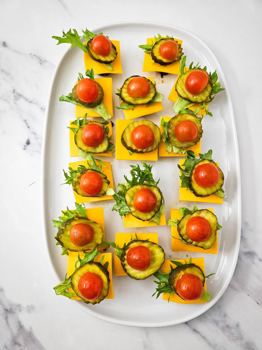 cooked ground beef mini patties topped with cheese and lettuce and pickle and tomato