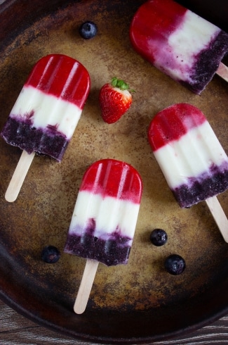 3 popsicles on a pan with strawberry nearby