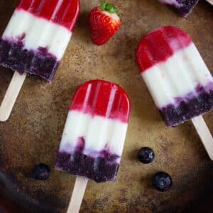 3 popsicles on a pan with strawberry nearby
