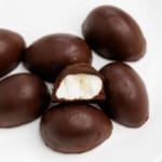 Protein Chocolate Marshmallow Eggs stacked on a white plate, one with bite taken out front and center