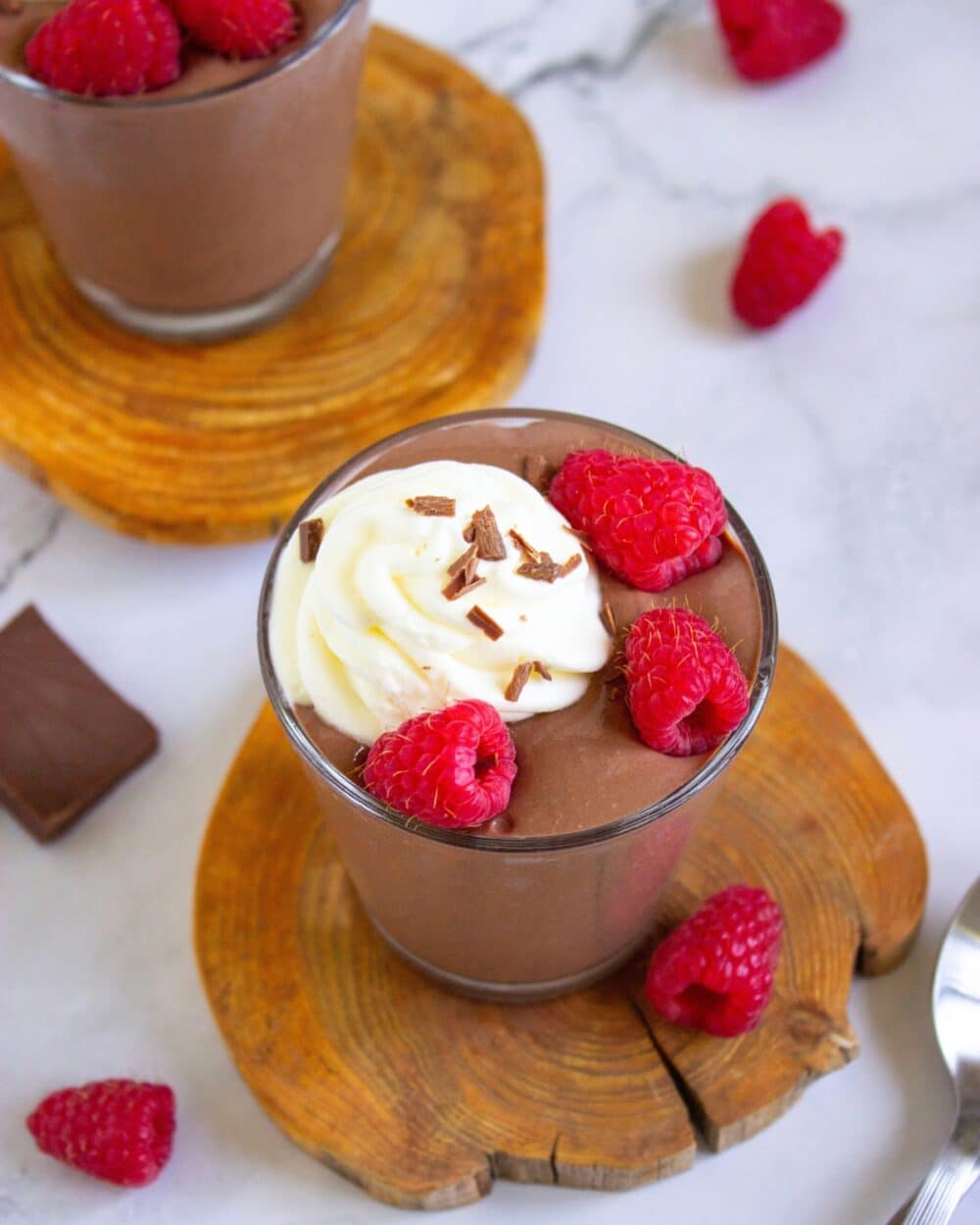 Chocolate Peanut Butter Cottage Cheese Pudding on a wooden board with raspberries