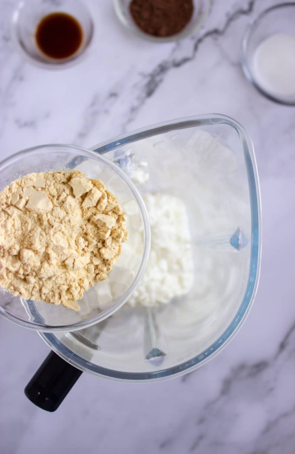 adding protein powder to a blender
