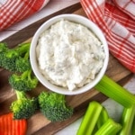 Cream Cheese Veggie Dip with broccoli, celery and carrots nearby on a brown cutting board