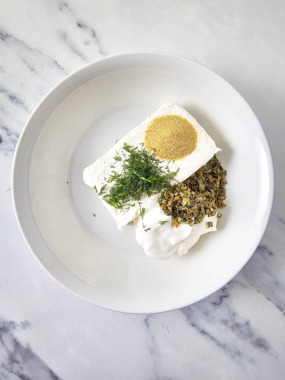 cream cheese and sour cream herbs and spices in a bowl