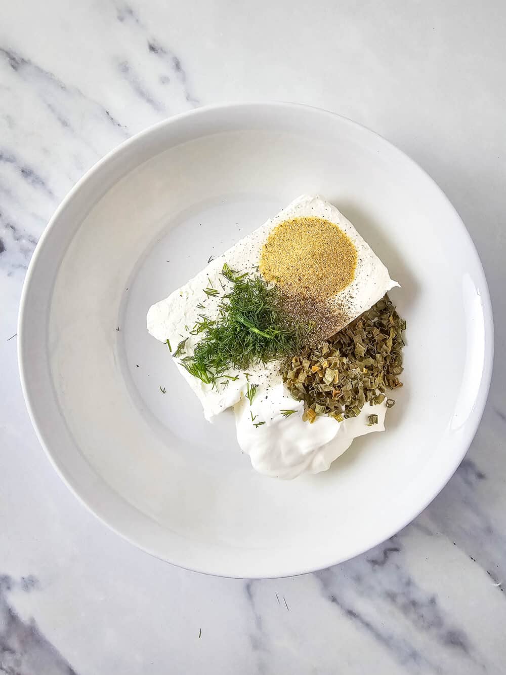 cream cheese and sour cream herbs and spices in a bowl
