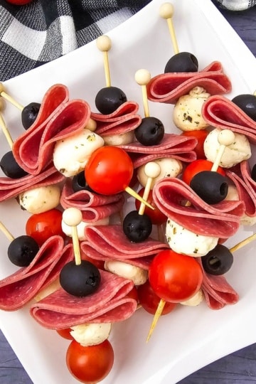 overhead view of Keto Antipasto Skewers on a white plate and blue background