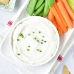 Cottage Cheese Ranch Dip with carrots and snap peas on a white serving plate overhead