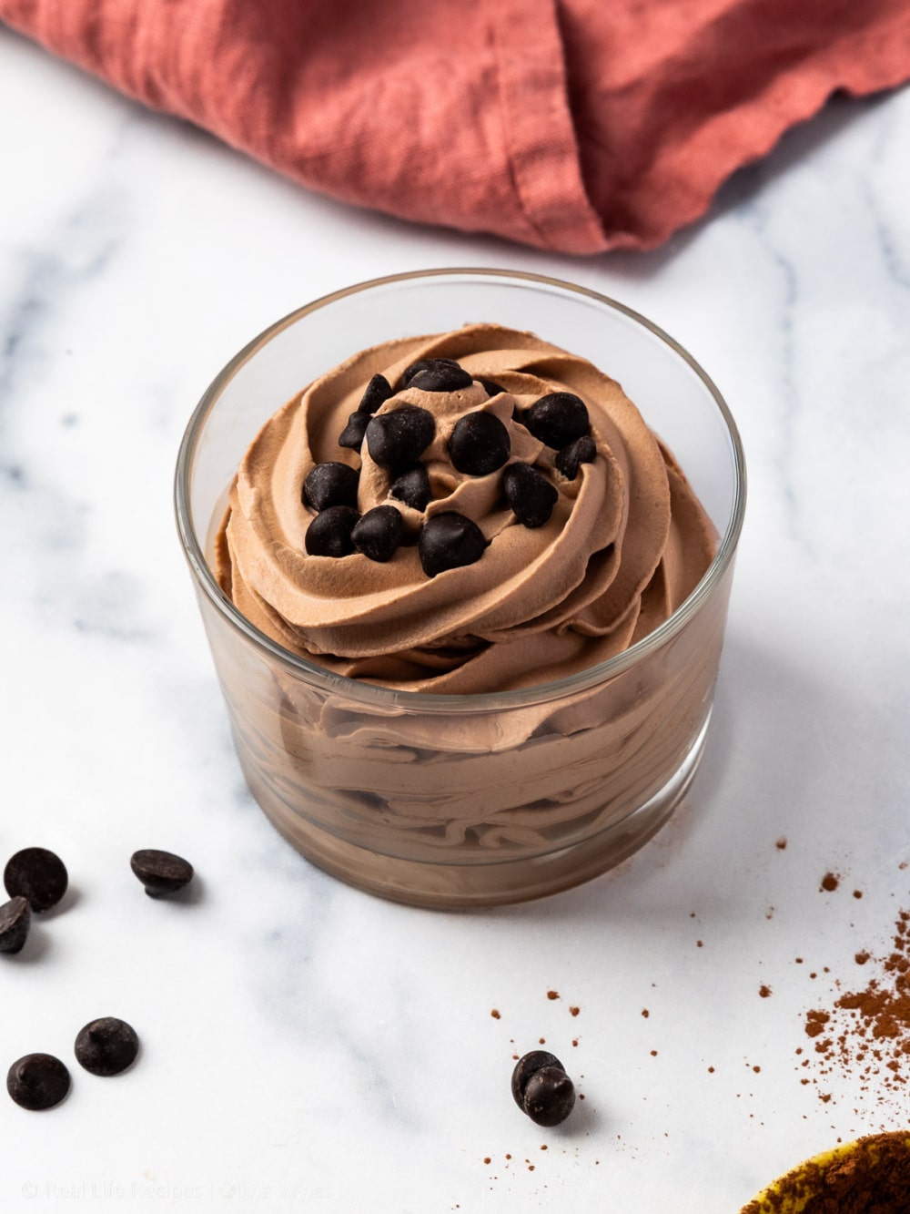 whipped keto chocolate mousse piped neatly into a dessert glass topped with dark chocolate chips, 45 degree angle
