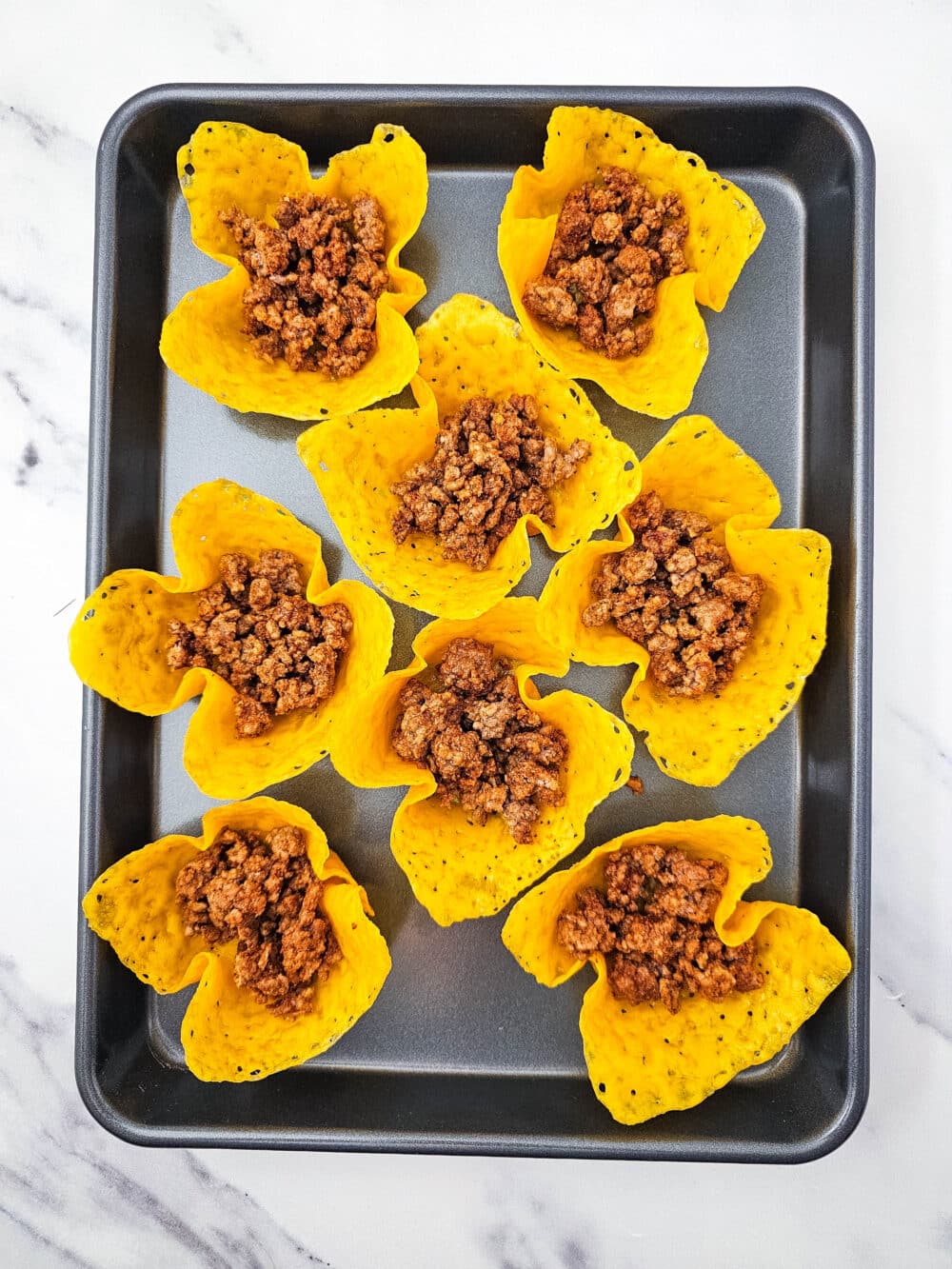 baked cheese fitted into muffin tin with seasoned ground beef added