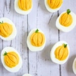 pumpkin deviled eggs on a white wood background