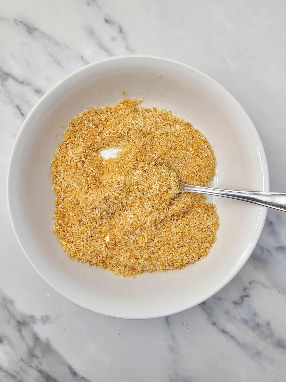 Bowl of crushed pork rinds mixed with grated parmesan and salt.
