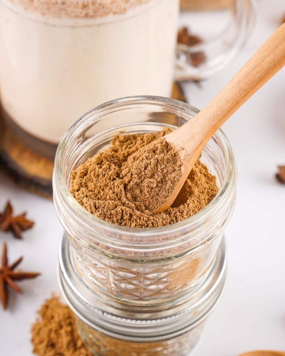 Close-up of chai spice mix in a glass jar with a wooden spoon