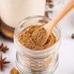 Close-up of chai spice mix in a glass jar with a wooden spoon