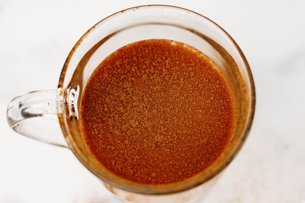 Overhead close-up of protein chai latte in a clear mug topped with cinnamon.