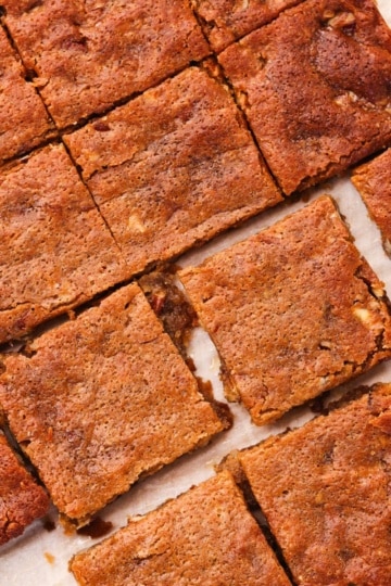 Golden baked maple pecan blondies cut into squares on a baking pan.
