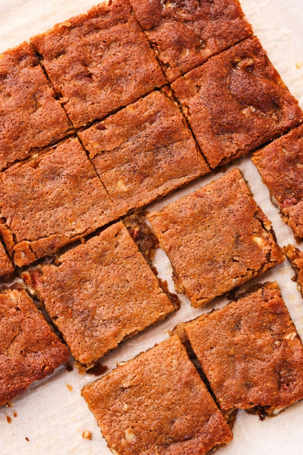 Baked protein maple pecan blondies cut into squares on parchment paper.
