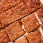 Baked protein maple pecan blondies cut into squares on parchment paper.