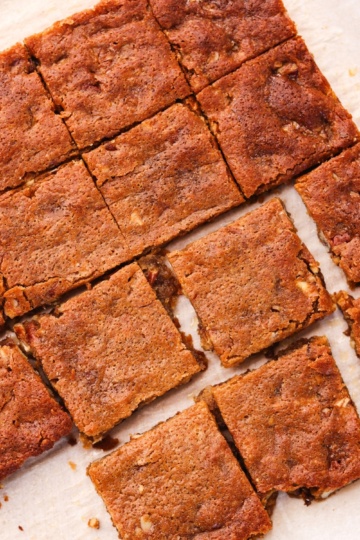 Baked protein maple pecan blondies cut into squares on parchment paper.