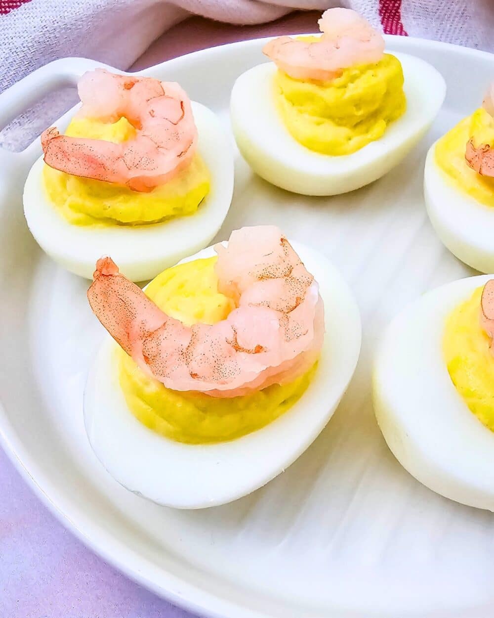 Plate of shrimp deviled eggs, each topped with a small shrimp, ready to serve.
