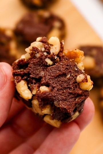 a piece pumpkin and brownie batter roll with walnuts being held in hand