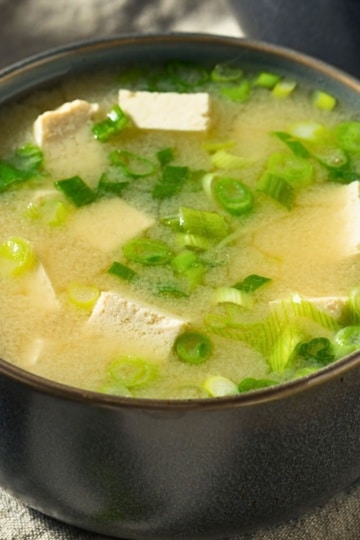 Japanese miso soup with tofu and green onions in a dark bowl