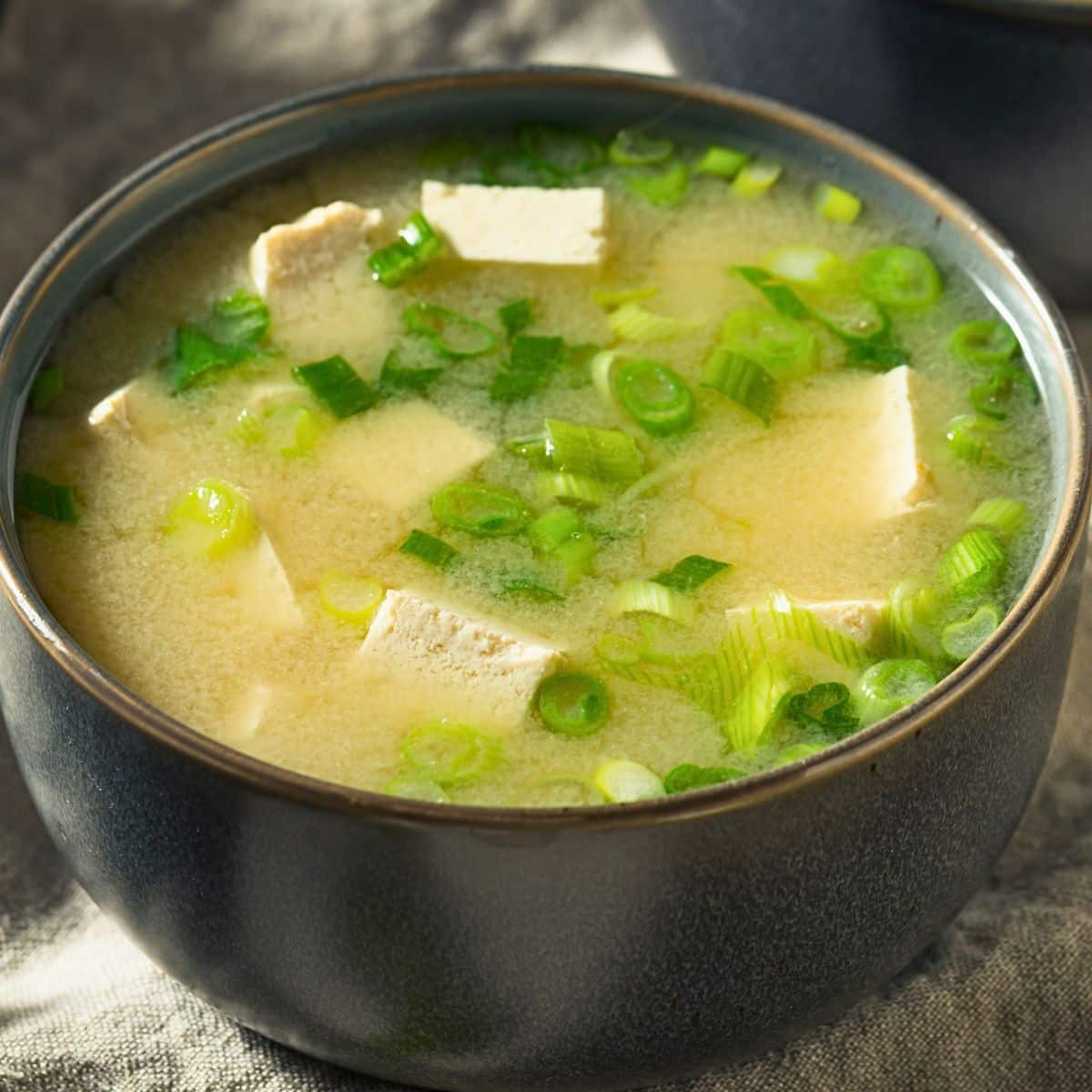 Japanese miso soup with tofu and green onions in a dark bowl