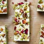 Close-up overhead view of single pistachio protein bar showing white chocolate coating with chopped pistachios and dried rose petal garnish