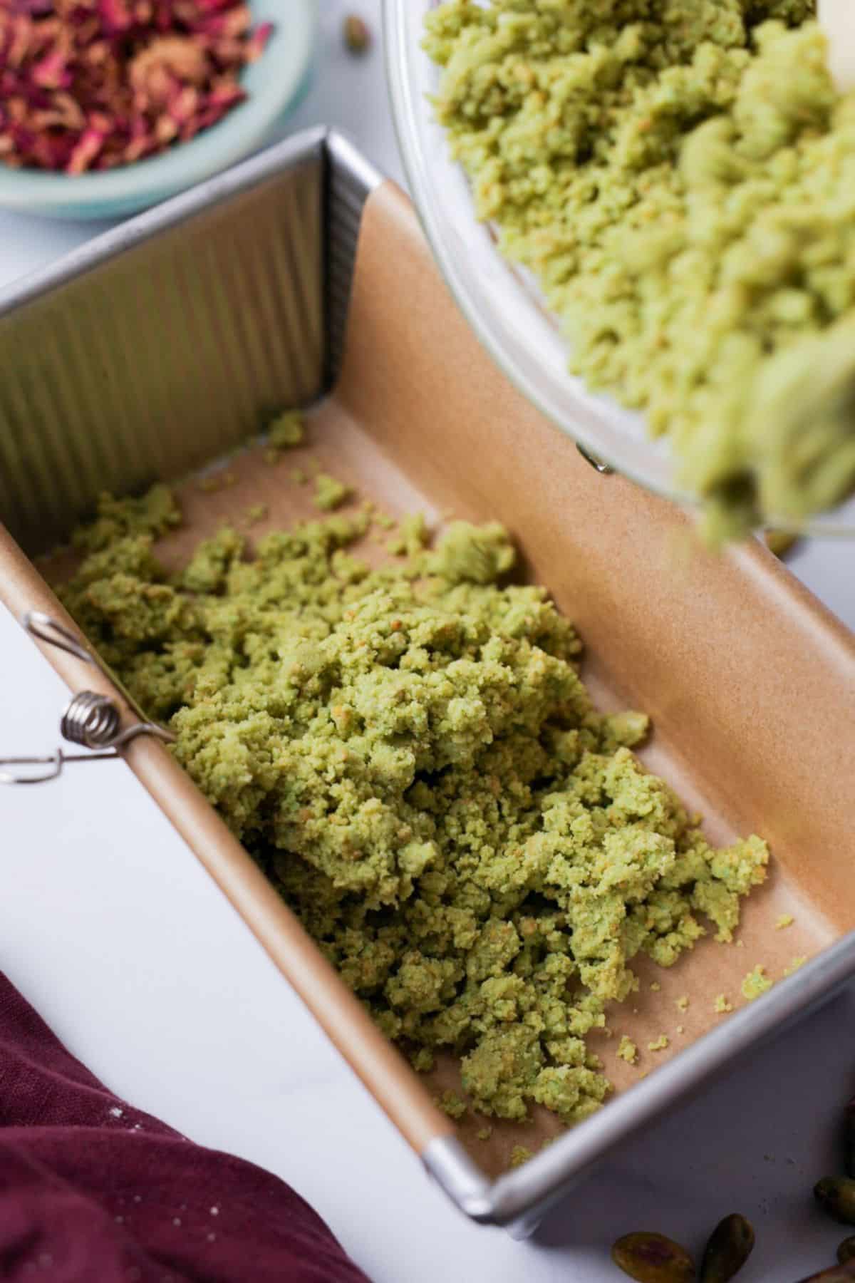 Green pistachio dough pressed into parchment-lined loaf pan