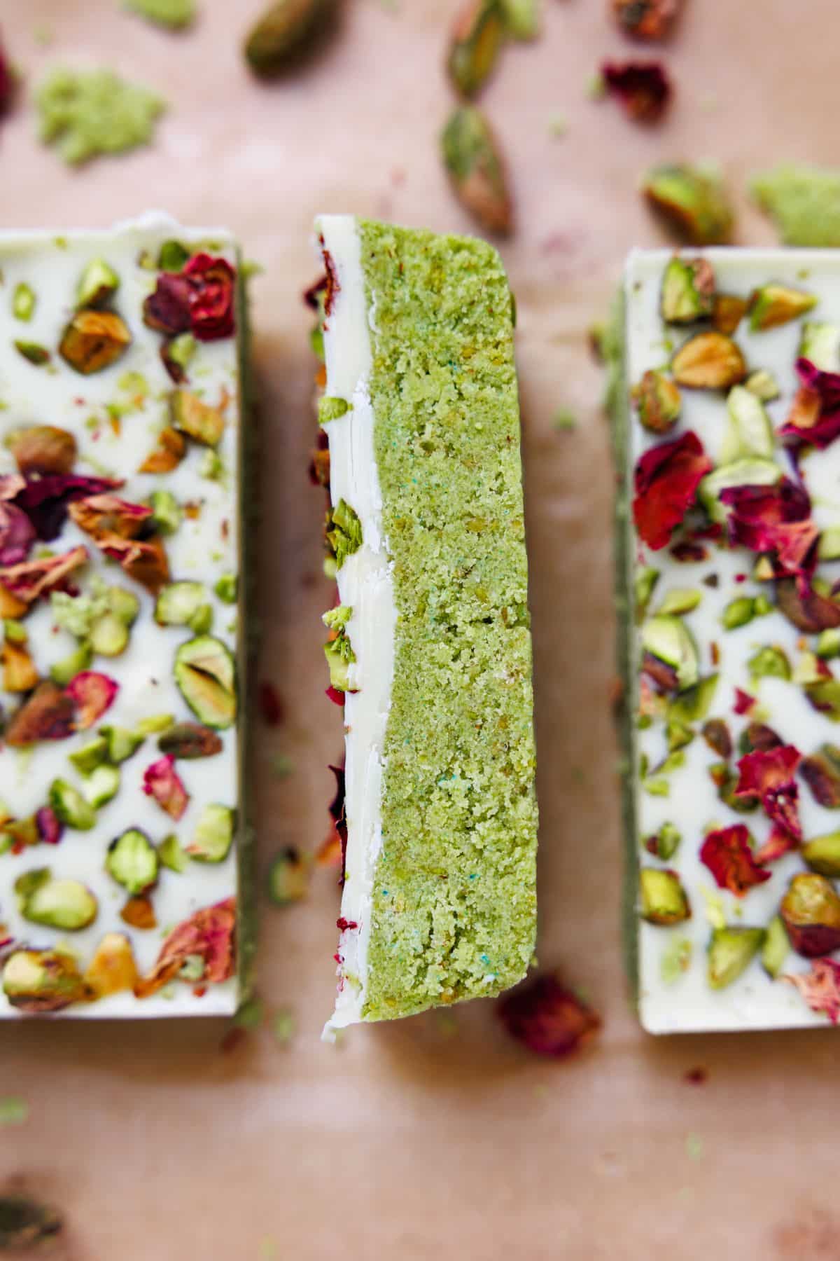 Single pistachio protein bar standing upright showing dense green pistachio layer beneath white chocolate coating
