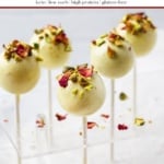 Pinterest graphic for keto pistachio cake pops showing white chocolate dipped cake pops with crushed pistachios and rose petals on sticks in acrylic stand