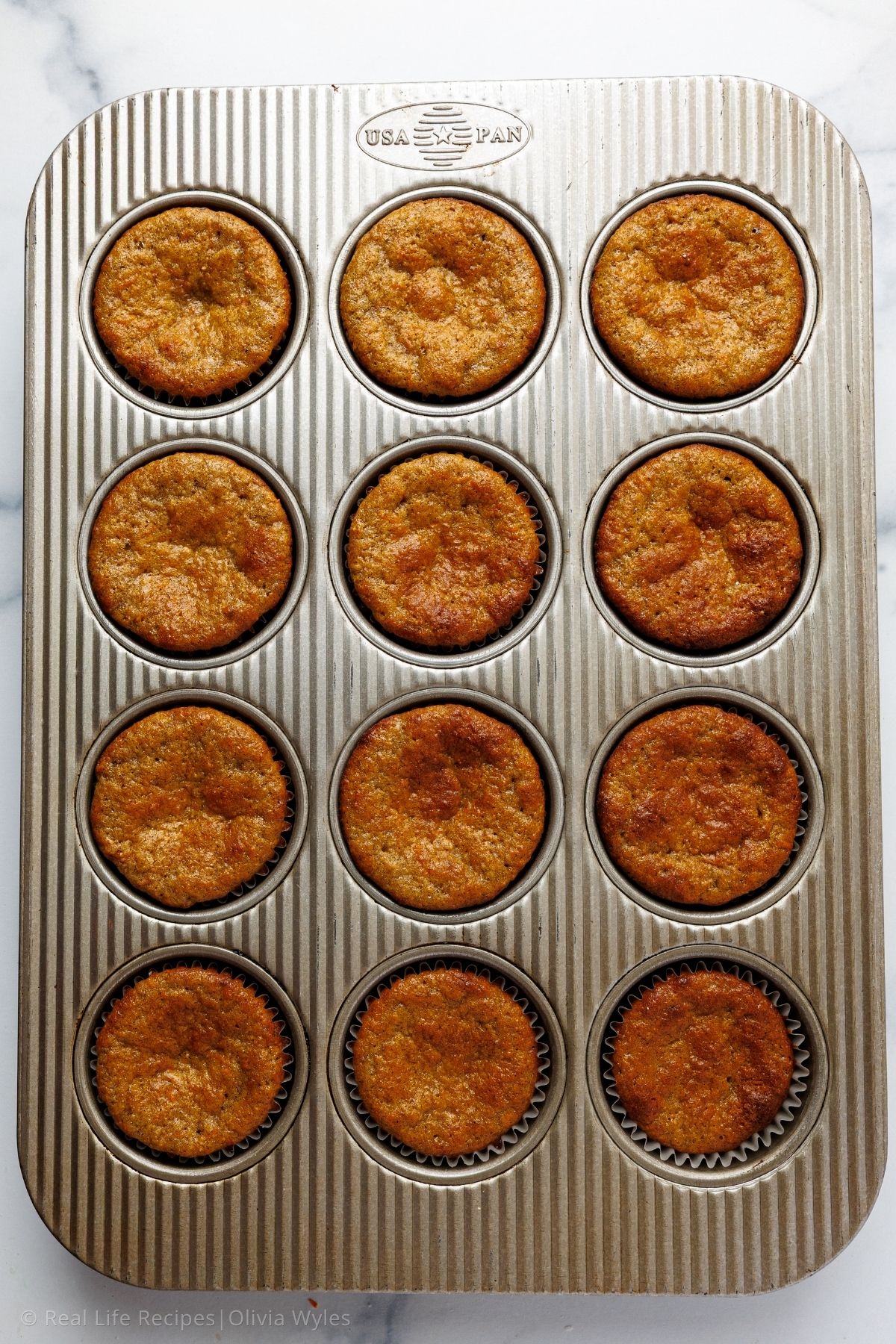 Twelve golden brown carrot cake cupcakes fresh from the oven in a USA Pan muffin tin