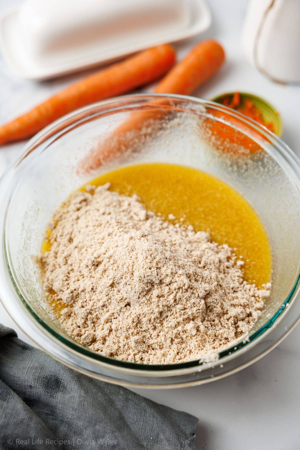 Dry flour mixture poured into the wet ingredients in a glass mixing bowl