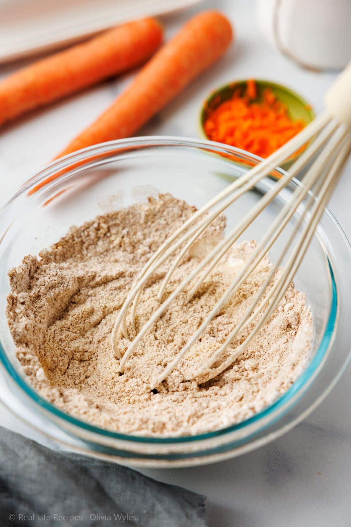Dry ingredients whisked together in a glass bowl with a whisk resting inside